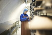 Arbeiterin aktualisiert digitales Tablet, während sie Stapel von Saatkörben in unterirdischer Tunnelgärtnerei vorbereitet, London, Großbritannien — Stockfoto