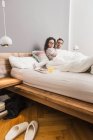 Paar liegt mit Frühstück auf Tablett im Bett — Stockfoto