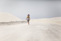 Мальчик, бегущий по Национальному парку Уайт-Сэндс, Алагордо, Нью-Мексико, США — стоковое фото