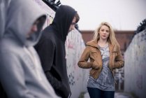 Teenagers standing against wall with graffiti — Stock Photo