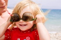 Bebé niña usando gafas de sol al revés - foto de stock
