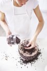 Donna spruzzando gocce di cioccolato sulla torta — Foto stock