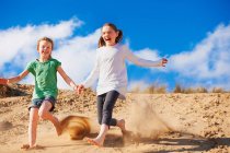 Дві дівчини біжать на піщаній дюні — стокове фото