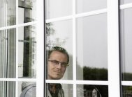 Retrato do homem adulto médio olhando pela janela — Fotografia de Stock