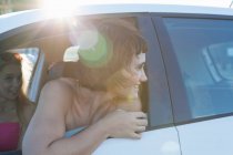 Женщина смотрит через окно машины через плечо — стоковое фото
