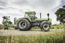 Farmer driving tractor on rural road — Stock Photo