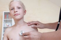 Niño siendo examinado por el médico con estetoscopio - foto de stock