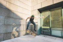 Молодой городской скейтбордист делает трюк со скейтбордингом в углу — стоковое фото