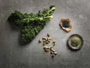 Top view of leafy vegetables, cardamom pods and ground supplements — Stock Photo