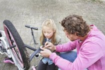 Батько і дочка ремонтують велосипед на відкритому повітрі — стокове фото