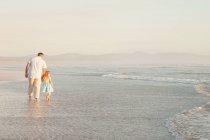 Батько і дочка тримаються за руки в океані — стокове фото