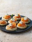 Smoked salmon and cream cheese on blinis with chive and black pepper garnish — Stock Photo