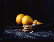Печенье с шоколадным покрытием и апельсины на винтажном столе — стоковое фото