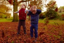 Jungen werfen Herbstblätter — Stockfoto