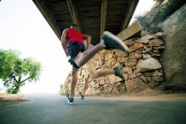Two male friends, running under bridge, rear view, low angle view — Stock Photo