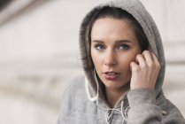 Жінка-бігунка в сірому халаті слухає музику на навушниках — стокове фото