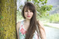 Porträt einer jungen Frau lehnt an Baumstamm — Stockfoto
