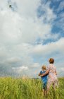 Visão traseira da mãe e da filha voando pipa no campo — Fotografia de Stock
