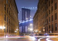 Manhattan Bridge y apartamentos en la ciudad por la noche, Nueva York, Estados Unidos - foto de stock