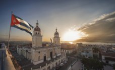 Bandeira cubana acenando sobre a Plaza de la Catedral ao pôr do sol, Santiago de Cuba, Cuba — Fotografia de Stock