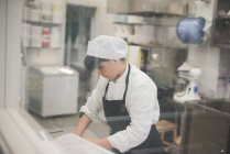 Bäckerin rollt Teig in Küche — Stockfoto
