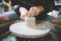 Vista frontal cortada do homem adulto médio fazendo argila na roda de cerâmica — Fotografia de Stock