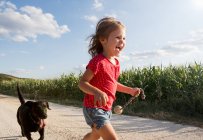 Chica y perro corriendo por el campo - foto de stock
