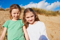 Porträt zweier Mädchen, die am Strand in die Kamera schauen — Stockfoto