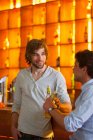 Двое мужчин стоят в баре с бутылками пива — стоковое фото