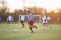Jogadores de futebol correndo atrás de bola em campo — Fotografia de Stock