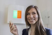 Женщина в офисе оптика держит пульт дистанционного управления смотрит в сторону улыбаясь — стоковое фото