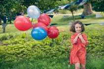 Девушка держит кучу воздушных шаров на улице — стоковое фото