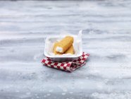 Fried chunky cod fish fingers in container on steel table — Stock Photo