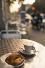 Copa de capuchino y croissant en la cafetería de la acera, Milán, Lombardía, Italia - foto de stock