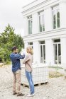 Visão traseira de comprimento total do arquiteto discutindo plantas para o exterior da casa com o proprietário apontando — Fotografia de Stock