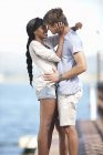 Young couple embracing on pier by water — Stock Photo