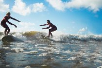 Two surfers riding wave — Stock Photo