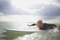 Пожилая женщина на доске для серфинга в море, паддлбординг — стоковое фото