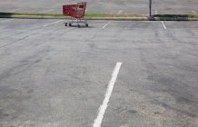 Парковка с одинокой тележкой для покупок — стоковое фото