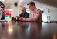 Padre e hijo usando tableta digital en el bar - foto de stock