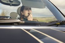 Woman applying lipstick in car mirror — Stock Photo