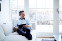 Mann entspannt sich auf Sofa und nutzt digitales Tablet — Stockfoto