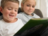 Дети читают вместе на диване — стоковое фото