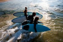 Cuatro personas llevando tablas de surf - foto de stock