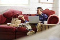 Mid adult man preparing parcels on sofa in picture framers showroom — Stock Photo