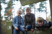 Tres chicos subiendo a la señal en el bosque - foto de stock