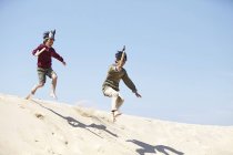Two boys, wearing fancy dress, playing on sand — Stock Photo