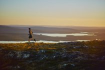 Man trail running on cliff top at sunset, Keimiotunturi, Lapland, Finland — Stock Photo