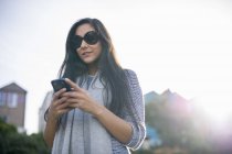 Молода жінка в сонцезахисних окулярах за допомогою смартфона — стокове фото