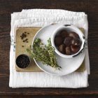 Chestnuts and thyme on book with black pepper — Stock Photo
